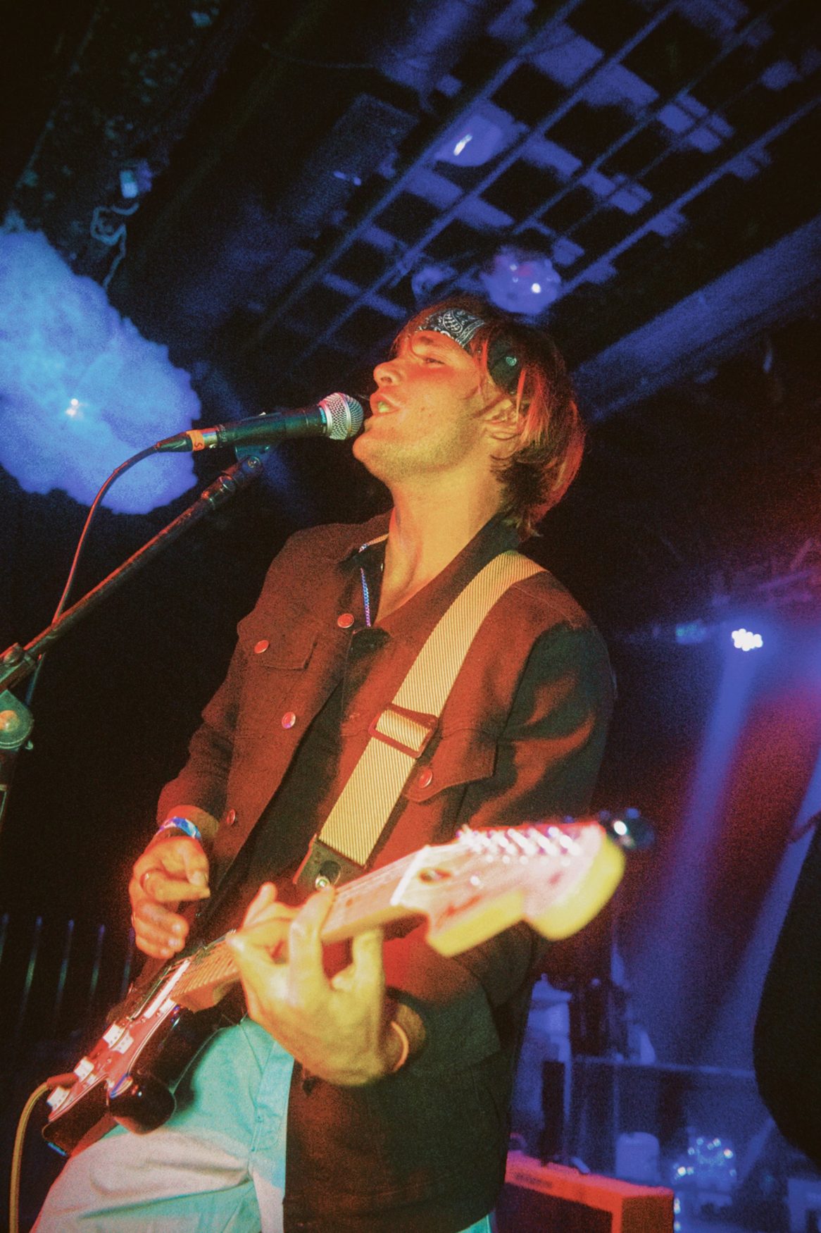 Marco singing with guitar under stage lights